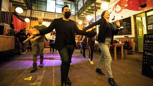 Un espacio interior amplio con techos altos y vigas a la vista, que incluye una zona de bar con taburetes y un menú en una pizarra.