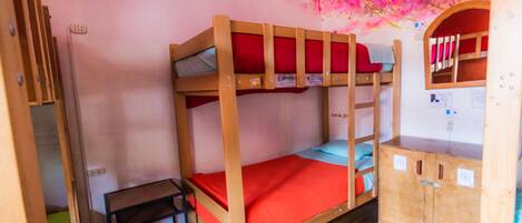 A bunk bed room with a desk and a small cabinet.