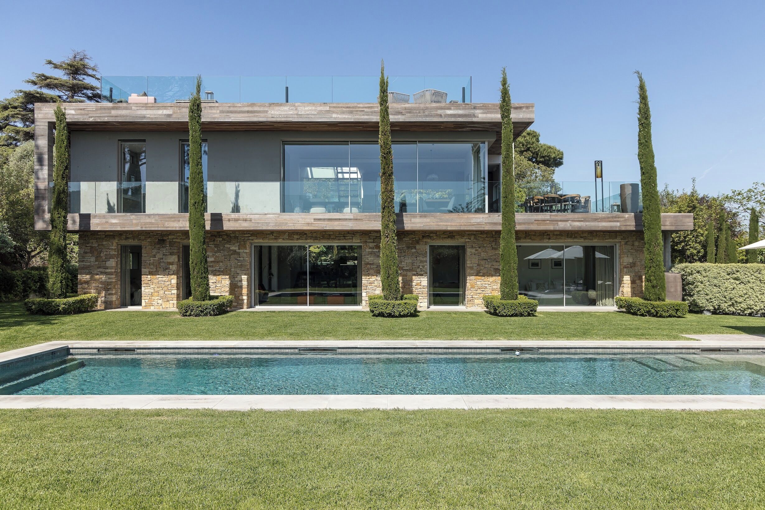 A modern two-story house with a swimming pool in the foreground.
