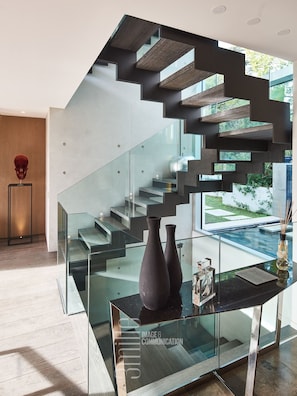 A modern staircase with glass railings and wooden steps.