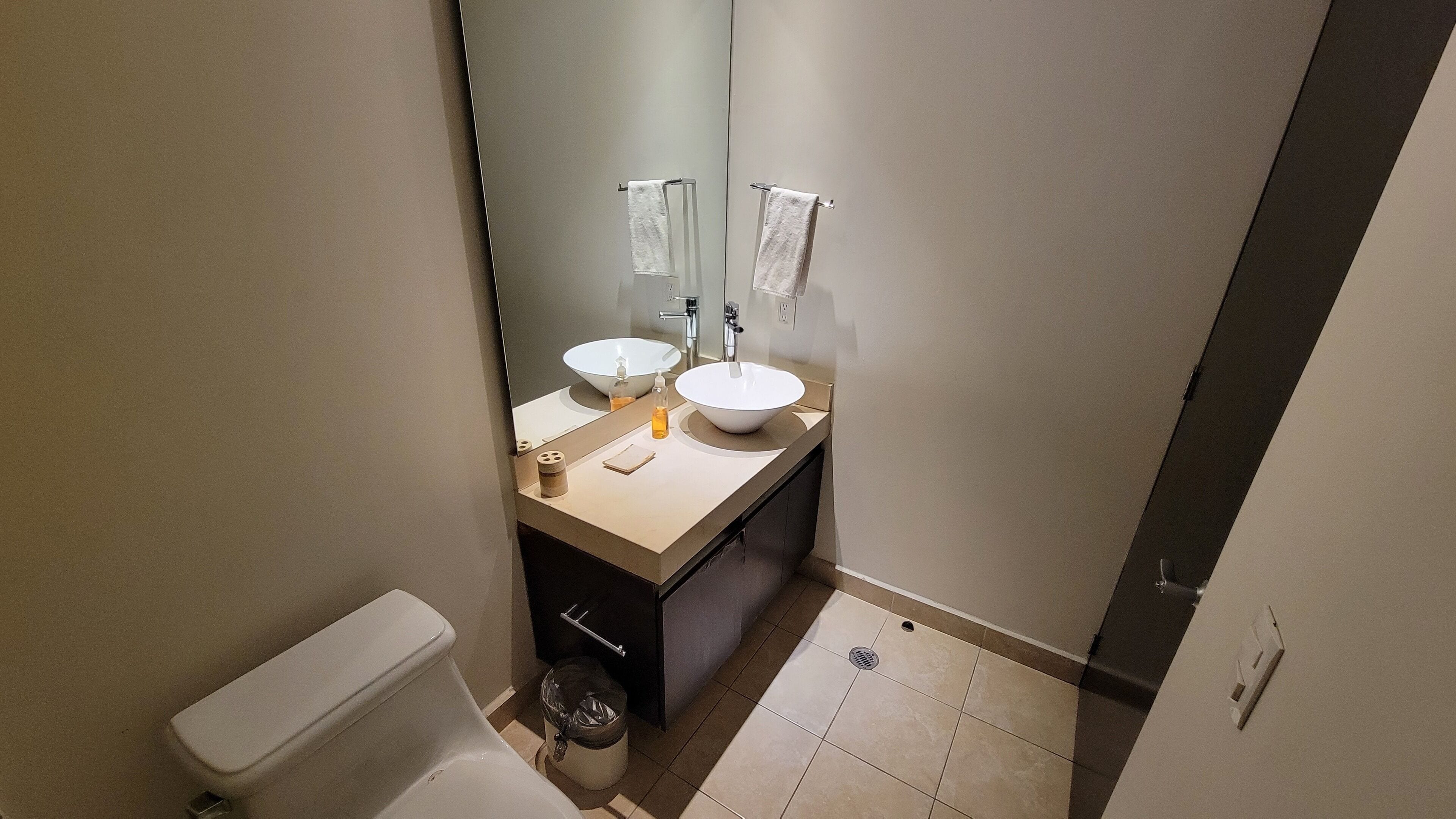 Een kleine badkamer met toilet, twee wasbakken en een spiegel.