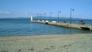 Un paseo marítimo con bancos e iluminarias que conduce a un faro.
