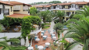 Un patio con mobiliario exterior, palmeras y un sendero de piedra.