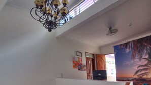 A staircase with wooden steps and a white handrail, leading to a landing with a ceiling fan and a wall-mounted TV. - Dragonfly Hostels Miraflores (Lima)