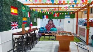 A cozy indoor space with a foosball table, bar stools, and a mural. Flags are displayed on the walls, and there are colorful bunting decorations. - Dragonfly Hostels Miraflores (Lima)