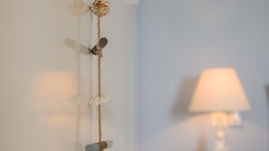 A wall with a string of decorative items, a lamp, and a wooden table.