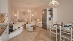A modern kitchen with a built-in refrigerator, microwave, and dining area with white chairs and a table.