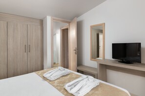 Une chambre d’hôtel avec un lit, une télévision, une armoire et un miroir.