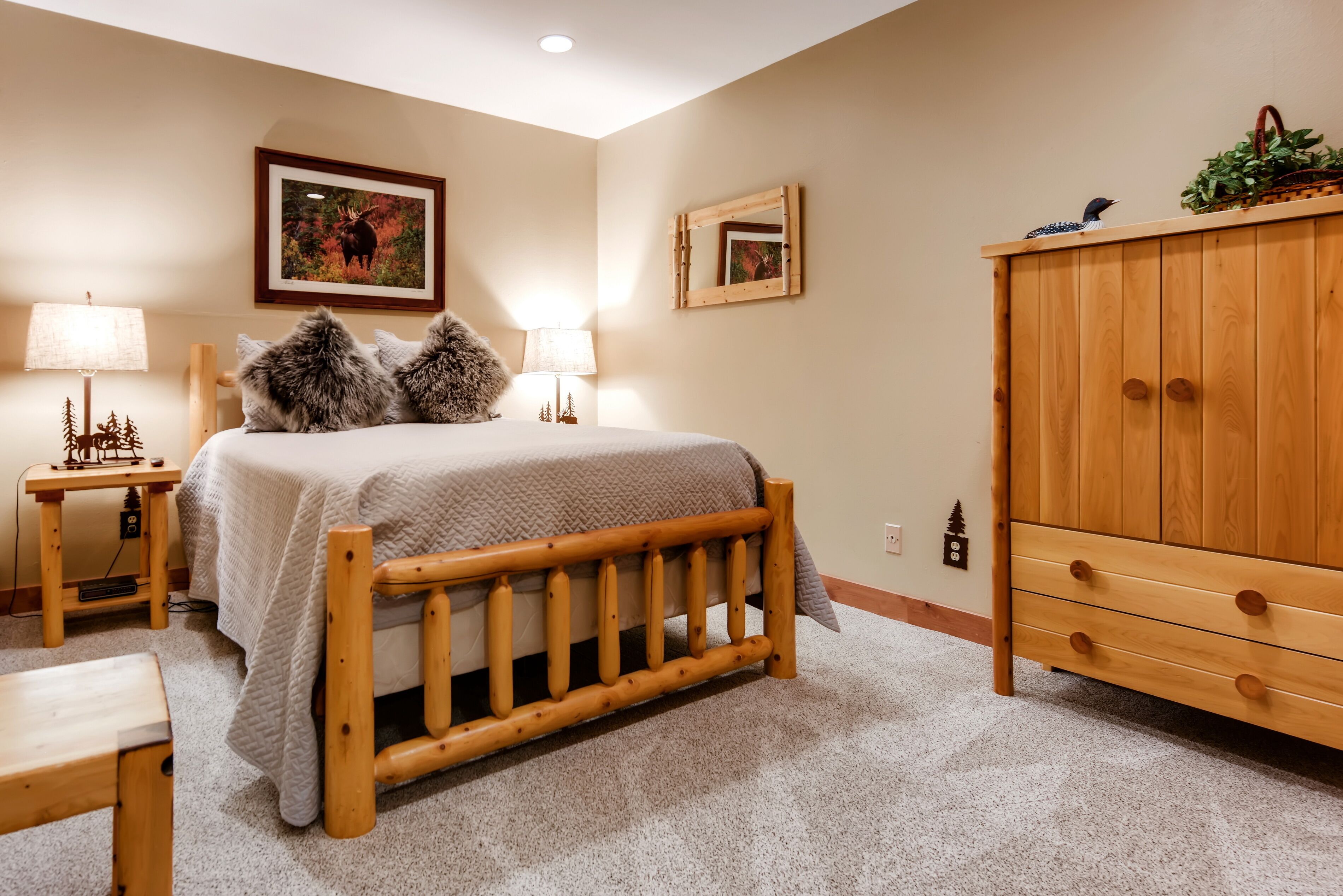 A bedroom with a wooden bed, two bedside tables with lamps, a wooden wardrobe, and a framed picture on the wall.