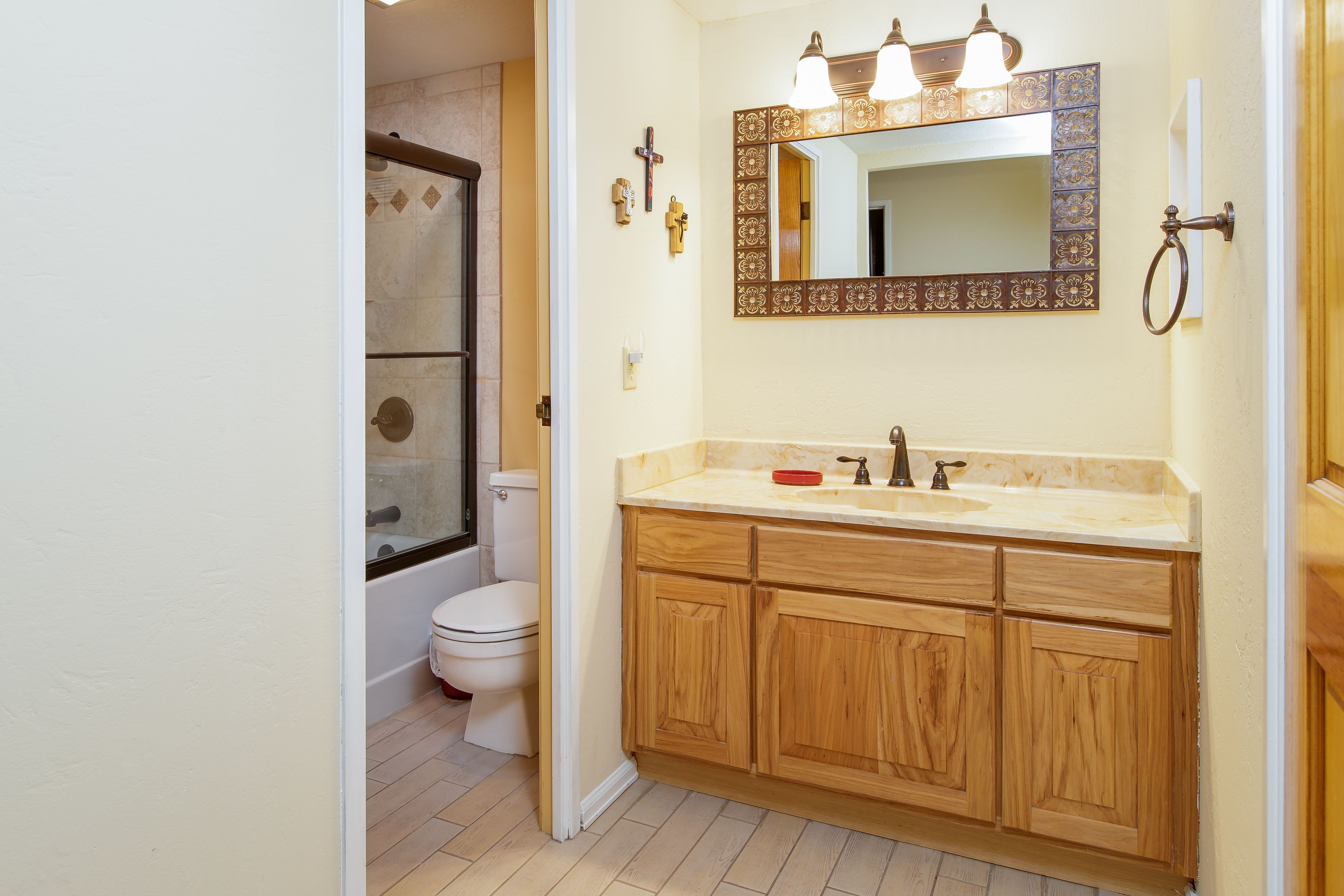 A bathroom with a wooden vanity, a mirror with decorative frame, and a shower area.