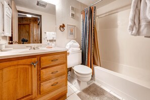 A bathroom with a wooden vanity, white sink, toilet, and bathtub. - Trails End Condos by CRMR (Breckenridge)