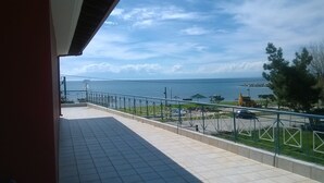 Un balcone con vista sul mare, un veicolo da costruzione e un'auto parcheggiata.