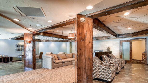 A spacious living area with a large sofa set, a patterned rug, and exposed wooden beams.