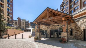 A hotel entrance with a wooden facade, stone walls, and a clear sky.
