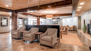 A spacious lobby with patterned armchairs, a black partition, and a tiled floor.