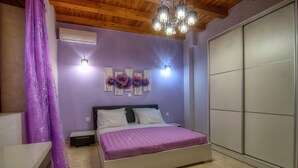 A bedroom with a bed, a nightstand, a dresser, a wardrobe, and a ceiling light fixture. - Green Paradise Luxury Villa In Crete  (Τζαννακιανά)