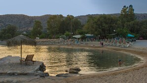 Ein Strand mit Pool, Liegestühlen und Sonnenschirmen.