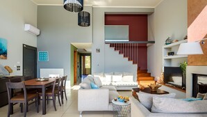 Ein modernes Wohnzimmer mit Essbereich, einer Treppe und einem Kamin.