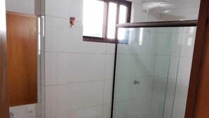 A bathroom with a toilet, sink, and glass shower enclosure. - Apartamento Central Setti (Foz do Iguaçu)