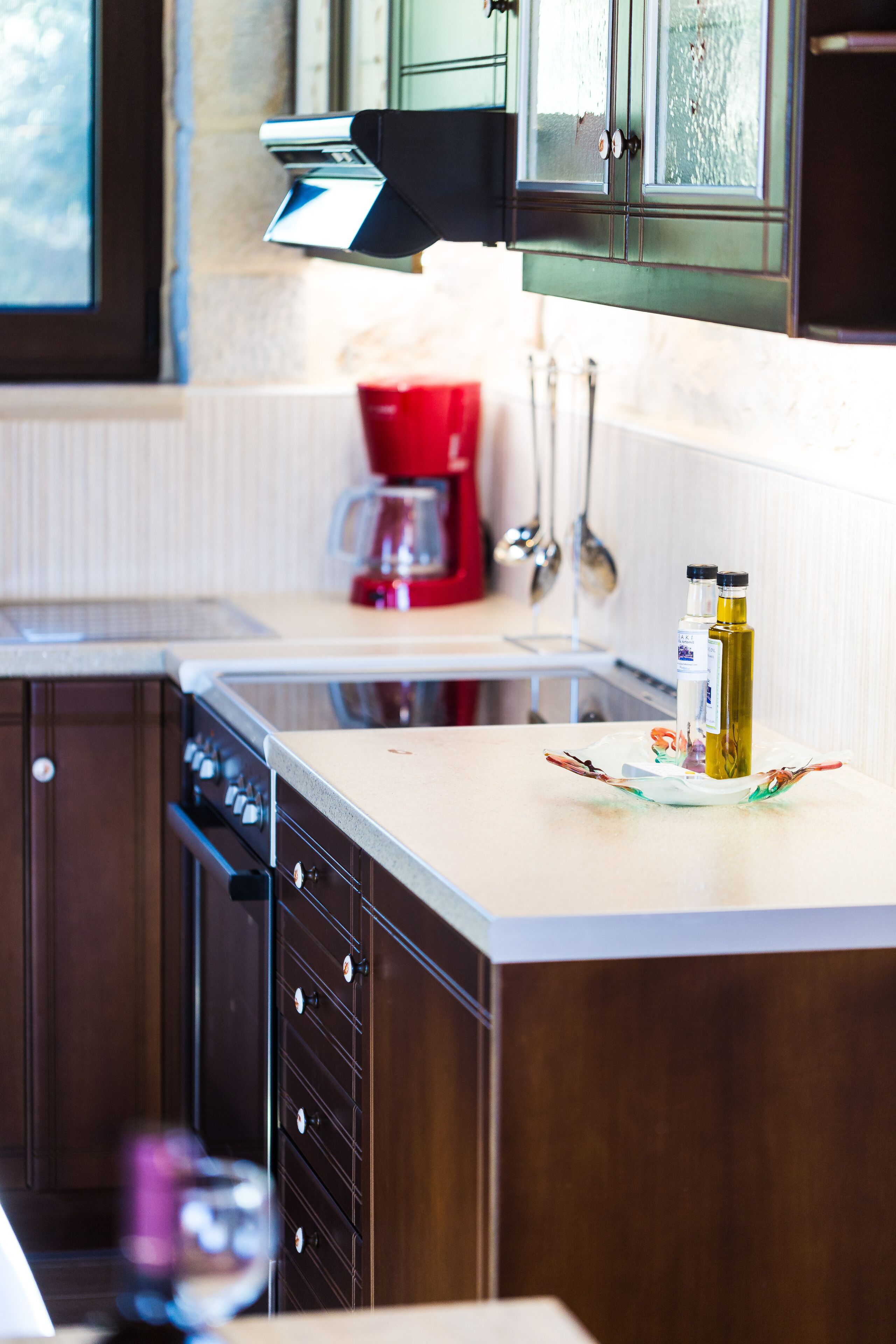 A kitchen with a built-in oven, a coffee maker, and two bottles of olive oil on the counter.