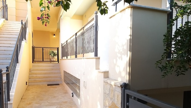 A staircase leading to a landing with a stone floor and a metal railing. - New, large apartm. with private garden, 3' to the sea and 5' to the city centre (Καλαμάτα)