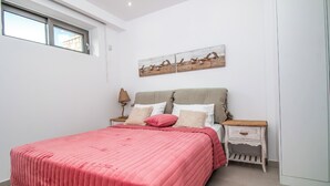 A bedroom with a bed, a nightstand, a lamp, a window, and a wall-mounted artwork. - Gregorys Luxury Villa in Kallithea (Αφάντου)