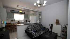 Ett modernt kök med vita skåp, en matplats med en svart soffa och ett svart soffbord.