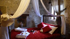 A bed with red bedding, white pillows, and a canopy. There are towels and a vase with flowers on the bed. - Crete villa Estia (Ρεθυμνο)