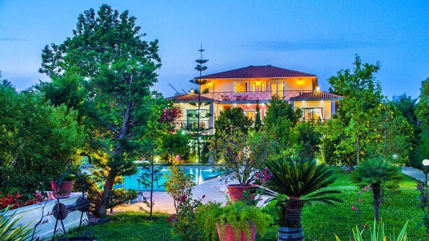 A two-story house with a swimming pool, surrounded by lush greenery and palm trees. - Top floor suite near to the town and close to the beach (Lefkada)