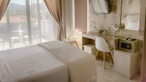 A hotel room with a bed, a desk, a chair, a TV mounted on the wall, and a window with curtains. - Alexandros villa with private pool (Νωπήγεια)