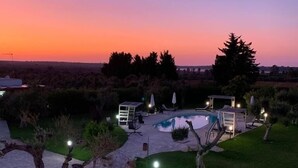 Un jardin aménagé avec une piscine, un espace salon couvert et un chemin en pierre.