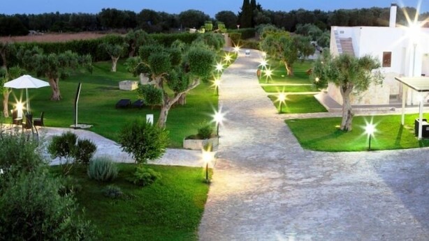 Un jardin bien entretenu, avec un chemin pavé menant à un bâtiment blanc.