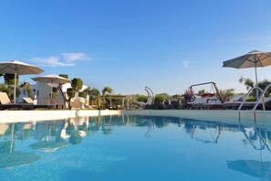 Een buitenzwembad, parasols bij het zwembad en ligstoelen