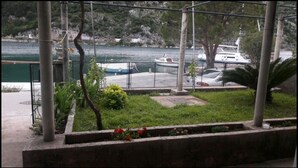 A view of a marina with boats docked, a grassy area with plants, and a fence. - Apartment Monkovic (Dubrovnik)