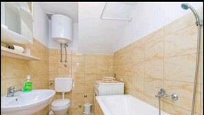 A bathroom with a sink, toilet, bathtub, and a shower. - Apartment Monkovic (Dubrovnik)