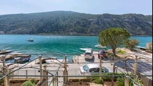 A coastal view with parked cars, boats, and a tree in the foreground. - Apartment Monkovic (Dubrovnik)