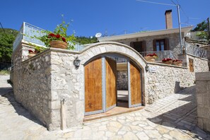 A stone building with a wooden door and potted plants. - Traditional 2 floor villa in the heart of Lefkada (Εγκλουβή)