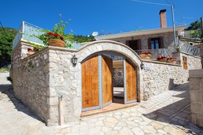A stone building with a wooden door and potted plants. - Traditional 2 floor villa in the heart of Lefkada (Εγκλουβή)