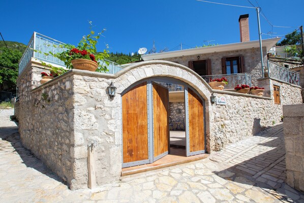 Un bâtiment en pierre avec une porte en bois et des plantes en pot.