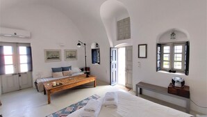 Une chambre avec un grand lit, un banc en bois, une table de chevet et une fenêtre donnant sur un beau paysage.