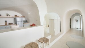 Une cuisine moderne avec des meubles blancs, un plan de travail en bois et un coin repas comprenant une table ronde et deux tabourets de bar.