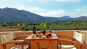 Una mesa preparada con comida y bebidas en un balcón con vista a la montaña.