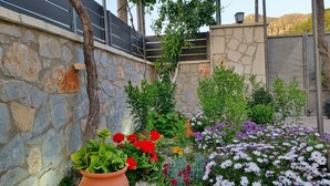 Muro de piedra con una maceta y diversas flores.