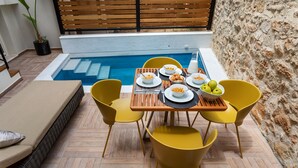Ein Essbereich am Pool mit einem Tisch für vier Personen, gelben Stühlen und einem Pool im Hintergrund.