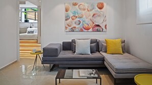 Ein modernes Wohnzimmer mit einem grauen Sofa, gelben und gemusterten Kissen, einem Couchtisch und einem großen abstrakten Gemälde an der Wand.