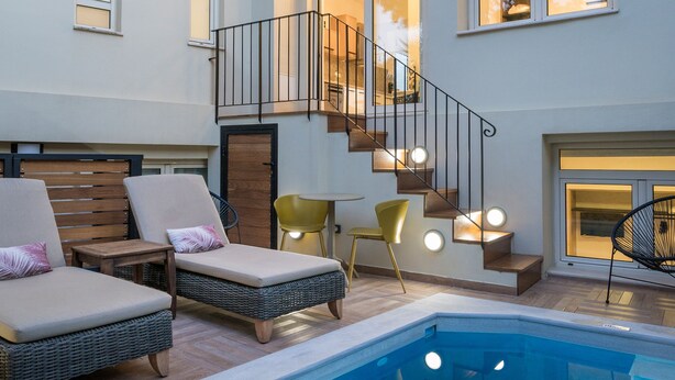 Ein moderner Poolbereich im Innenbereich mit Liegestühlen, einer Treppe und einem Kamin.