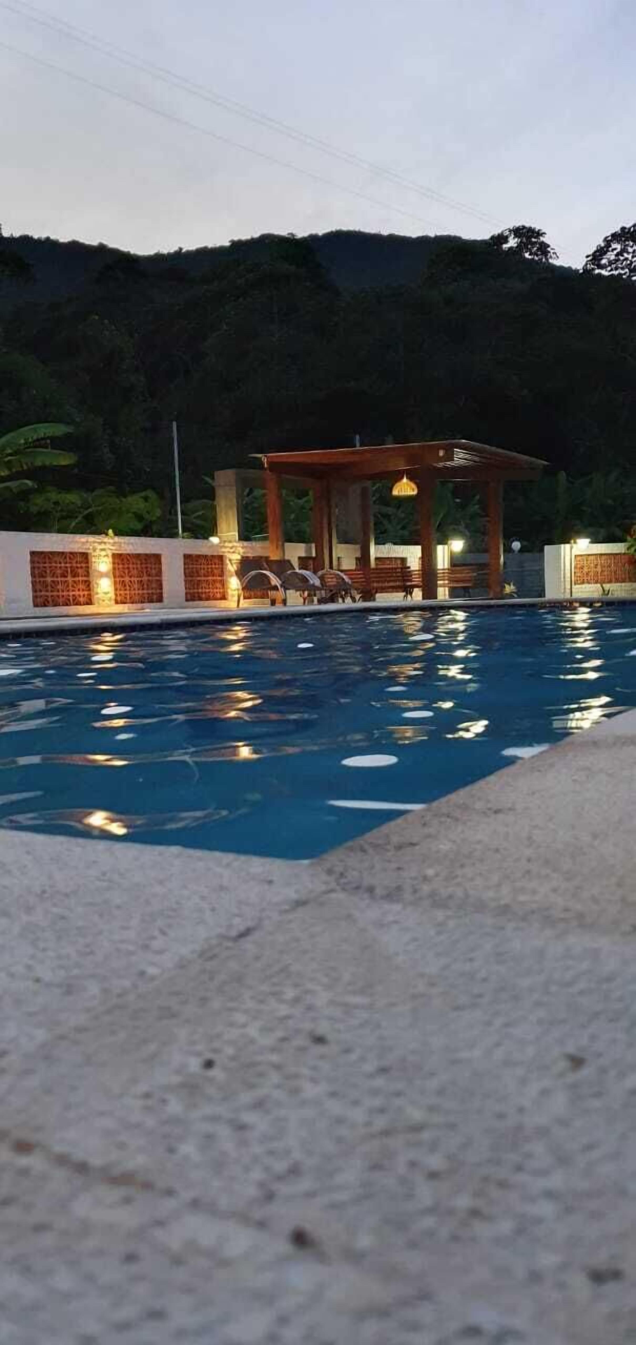 Una piscina con sillas de descanso y un pabellón.