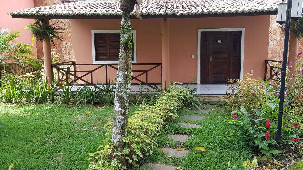 Una casa con techo de tejas, puerta de madera y un pequeño porche con barandilla.