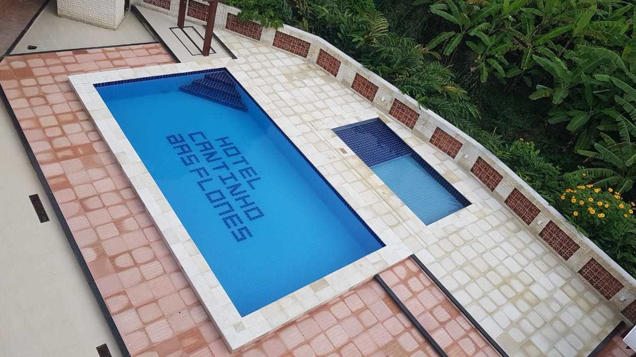 A rectangular swimming pool with a tiled border and a sign that reads "HOTEL INHABITS ARES FLUTES."