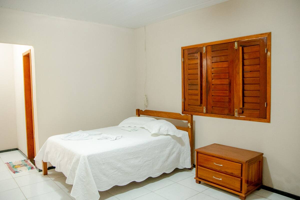 Une chambre à coucher comprenant un lit, une armoire en bois et une garde-robe avec des portes coulissantes.